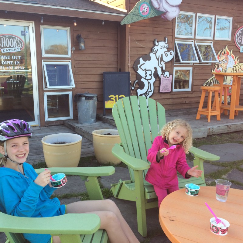 Two children sitting outside eating ice cream