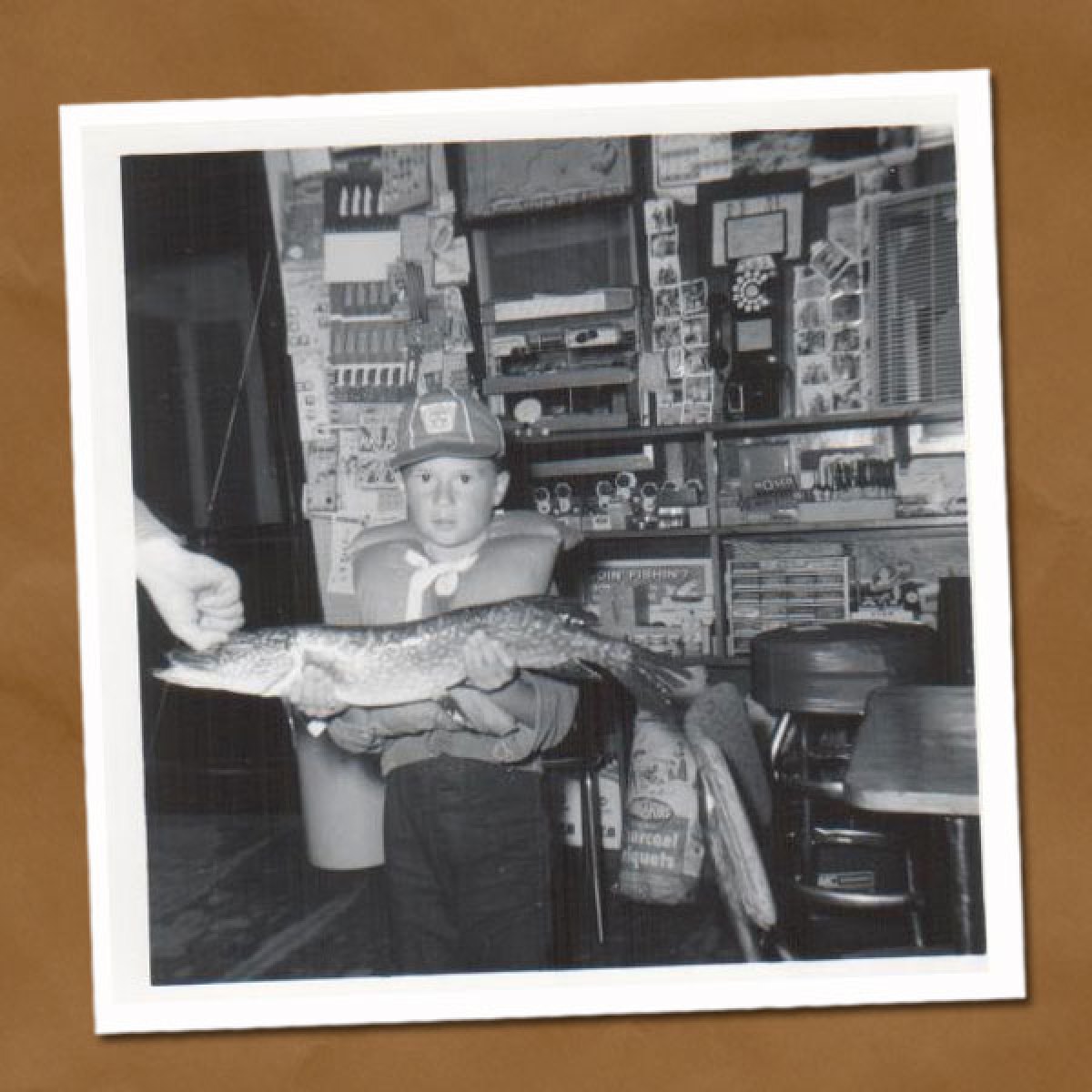 Black and white photo of little boy holding large fish inside Tally's Dockside