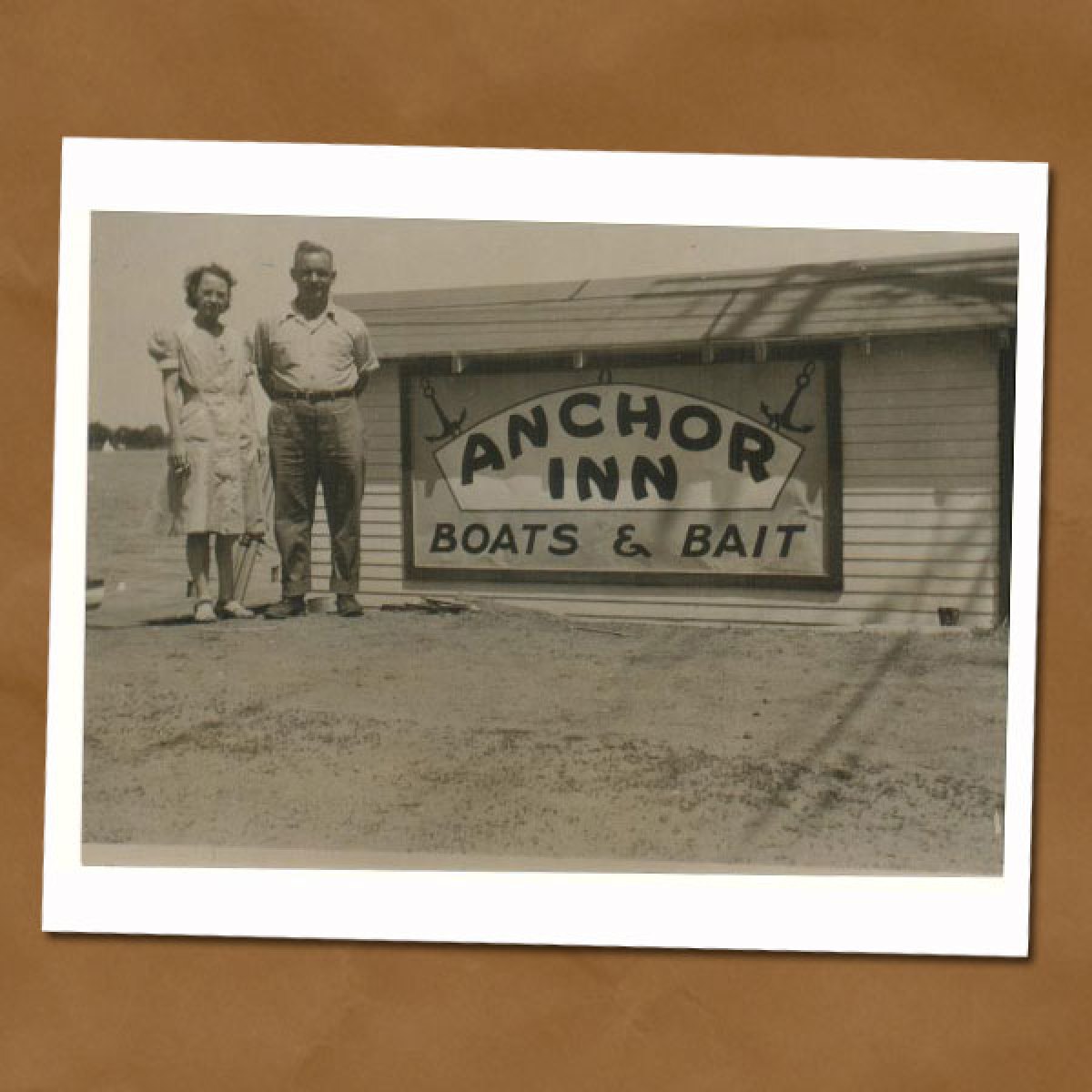 Black and white photo of couple standing next to sign that says,